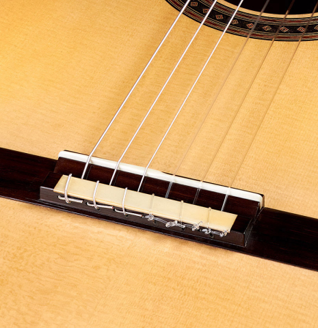 The bridge and saddle of a 2022 Jochen Rothel classical guitar made with spruce top and cherry back and sides