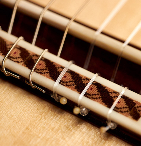 The bridge and saddle of a 2022 German Vazquez Rubio "Solista" classical guitar made of spruce and Indian rosewood