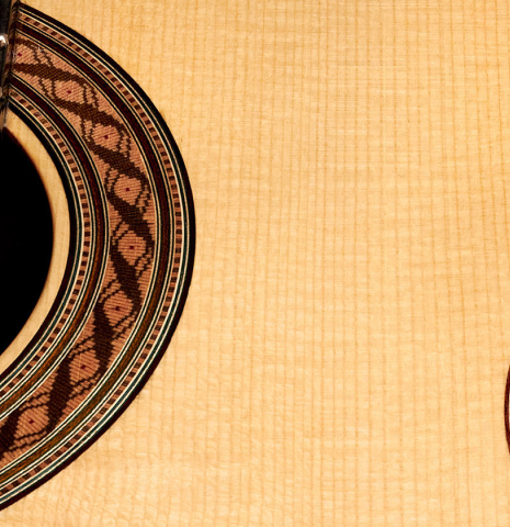 The soundboard and rosette of a 2022 German Vazquez Rubio "Solista" classical guitar made of spruce and Indian rosewood