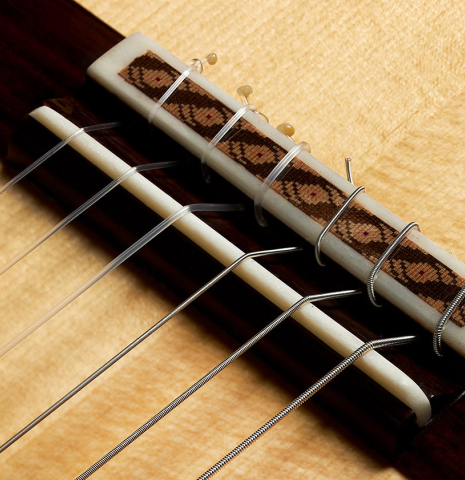 The bridge, tie-block and saddle of a 2023 German Vazquez Rubio "Solista" classical guitar made of spruce and Indian rosewood