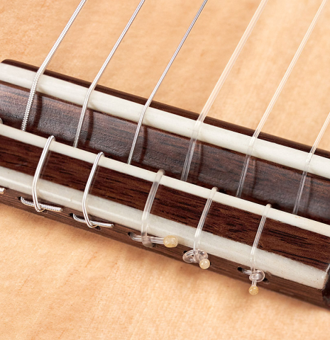 The tie-block, bridge and saddle of a 2022 German Vazquez Rubio "Classic Estudio" classical guitar made of spruce and Palo Escrito.