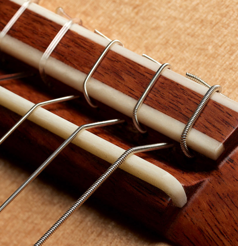 The bridge, tie-block and saddle of a 2024 German Vazquez Rubio "Classic Estudio" classical guitar made of spruce and Palo Escrito.