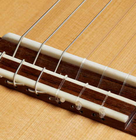 The bridge, tie-block and saddle of a 2025 German Vazquez Rubio "Classic Estudio" classical guitar made of spruce and Palo Escrito.