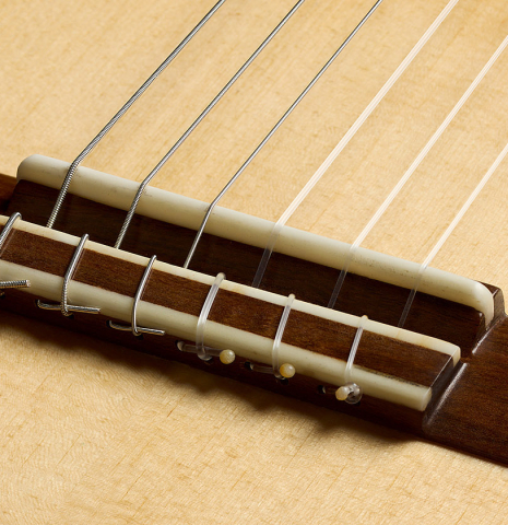 The bridge, tie-block and saddle of a 2025 German Vazquez Rubio "Classic Estudio" classical guitar made of spruce and Palo Escrito.
