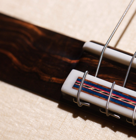 The bridge and saddle of a 2021 German Vazquez Rubio "Concert 635" classical guitar made with spruce and maple