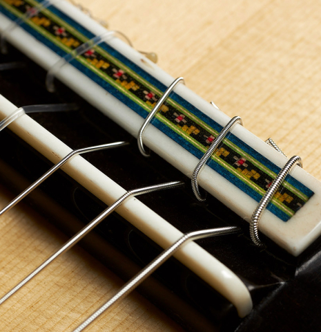 The bridge, tie-block and saddle of a 2023 German Vazquez Rubio "Concert 635" classical guitar made of spruce and maple