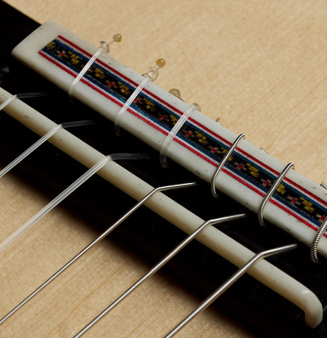 The bridge, tie-block and saddle of a 2025 German Vazquez Rubio "Concert 635" classical guitar made of spruce and maple