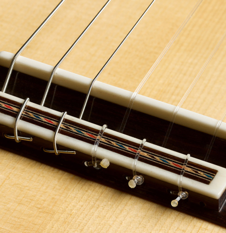 The bridge, tie-block and saddle of a 2026 German Vazquez Rubio "Concert 635" classical guitar made of spruce and maple