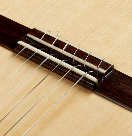 The bridge, tie-block and saddle of a 2024 German Vazquez Rubio "Divina" classical guitar made of spruce and palo escrito