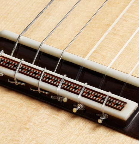 The bridge, tie-block and saddle of a 2024 German Vazquez Rubio "Solista" classical guitar made of spruce and Brazilian lacewood