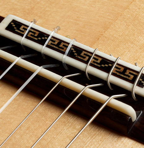 The bridge, tie-block and saddle of a 2024 German Vazquez Rubio "Solista" classical guitar made of spruce and Brazilian lacewood