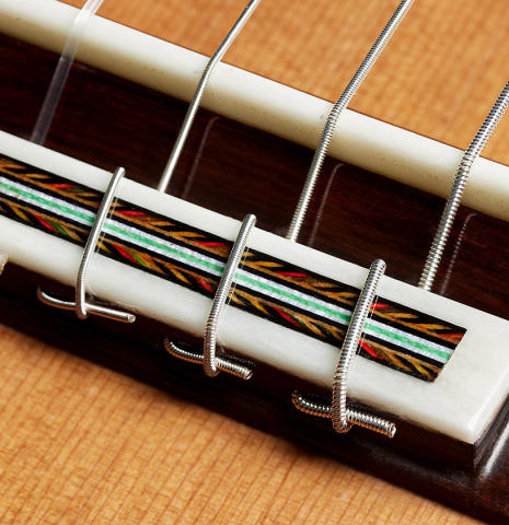 The bridge, tie-block and saddle of a 2025 German Vazquez Rubio "Solista 640 Lefty" classical guitar made of cedar and Indian rosewood