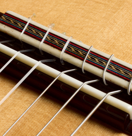 The bridge, tie-block and saddle of a 2025 German Vazquez Rubio "Solista 640" classical guitar made of spruce and Indian rosewood