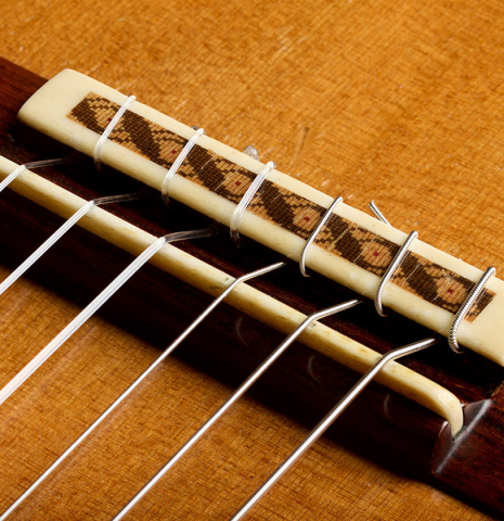 The bridge, tie-block and saddle of a 2020 German Vazquez Rubio "Solista" classical guitar made of cedar and Indian rosewood