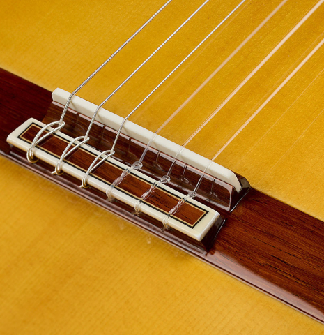 The bridge, tie-block and saddle of a 2025 Masaki Sakurai "Concert-R" classical guitar made of spruce and Indian rosewood
