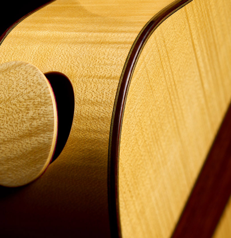 The side with removable soundport lid of a 2022 Douglass Scott "635" classical guitar made of spruce and maple