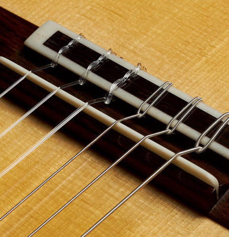 The bridge, tie-block and saddle of a 2023 Youri Soroka "1924 Santos, ex Segovia" classical guitar made of spruce and Indian rosewood