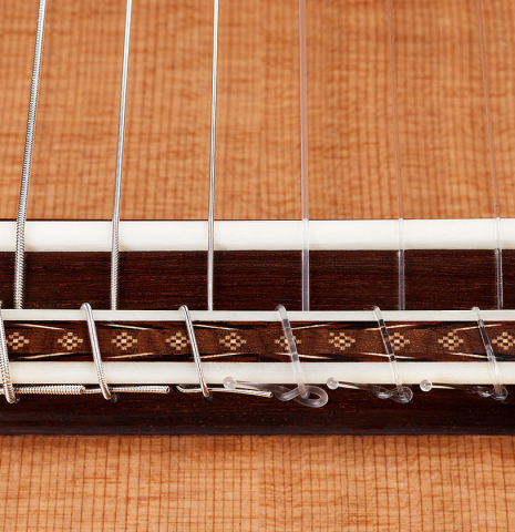 The bridge, tie-block and saddle of a 2024 Sebastian Stenzel classical guitar made of cedar and maple