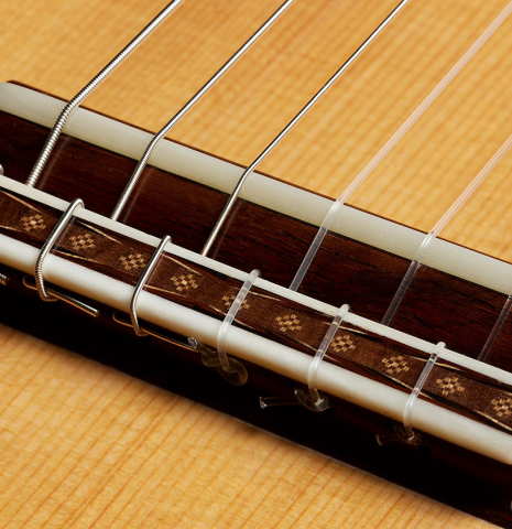 The bridge, tie-block and saddle of a 2023 Sebastian Stenzel classical guitar made of spruce and maple