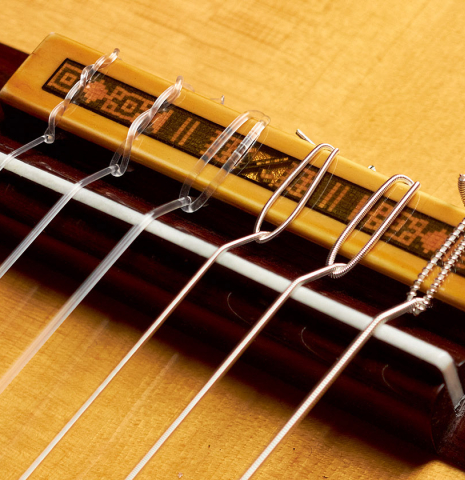 The bridge and saddle of a 2022 Andrea Tacchi "Homage to the Spanish School" classical guitar made with spruce and cypress wood
