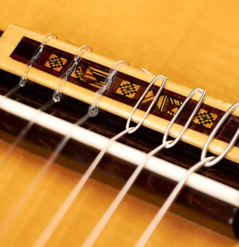 The bridge and saddle of a 2018 Andrea Tacchi "Omaggio a Robert Bouchet" classical guitar made of spruce and CSA rosewood