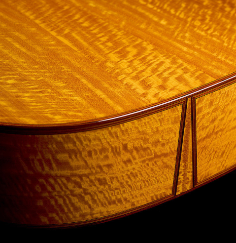 The back and sides at the foot of a 2025 Andrea Tacchi "Coclea Thucea - Satin" classical guitar made of cedar/spruce and satinwood