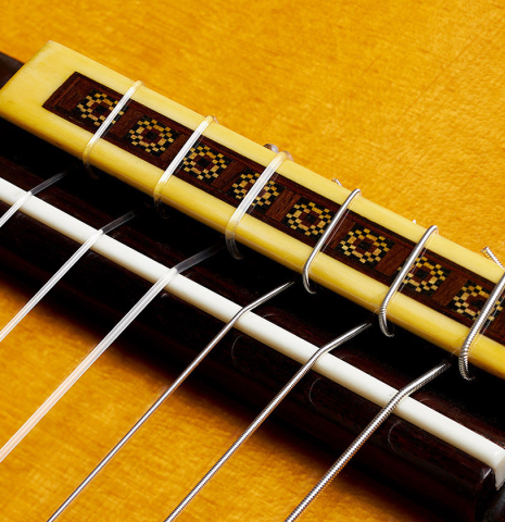 The bridge, tie-block and saddle of a 2010 Andrea Tacchi "Omaggio a Robert Bouchet" classical guitar made of spruce and CSA rosewood