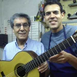 Mariano Tezanos and his nephew Sergio Tezanos holding a classical guitar in their Madrid workshop