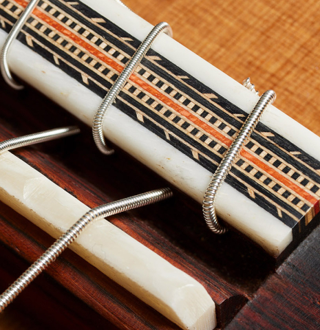 The bridge, tie-block and saddle of a 2023 Dake Traphagen classical guitar made of cedar and CSA rosewood