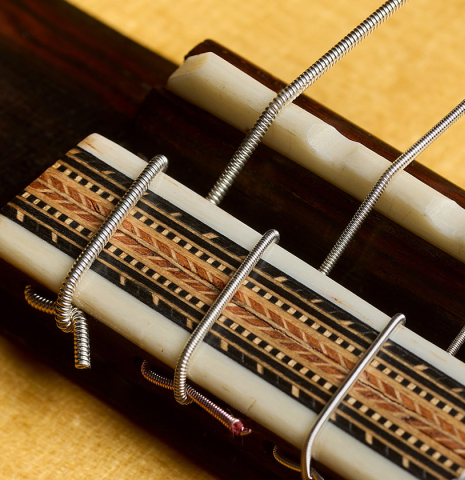 The bridge, tie-block and saddle of a 2005 Dake Traphagen classical guitar made of spruce and African rosewood