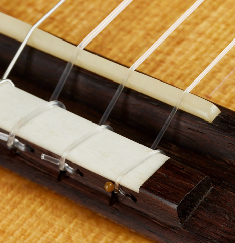The bridge, tie-block and saddle of a 2023 Mark Usherovich "Lattice" classical guitar made of spruce and pau ferro