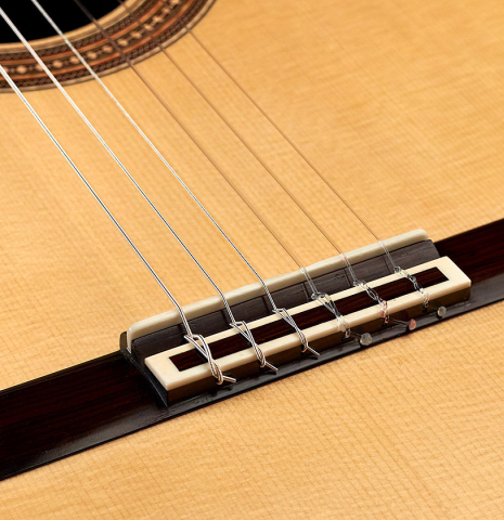 The bridge and saddle of a 2017 Angelo Vailati classical guitar made with spruce and Indian rosewood
