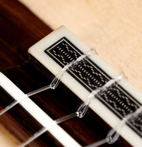 The bridge and tie-block of a 2022 Jose Vigil classical guitar made of spruce and CSA rosewood.