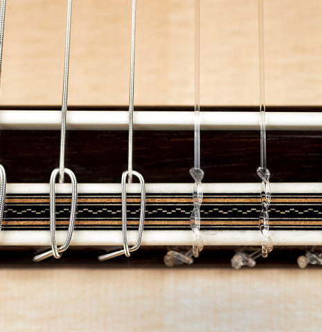 The bridge and tie-block of a 2023 Jose Vigil classical guitar made of spruce and CSA rosewood.