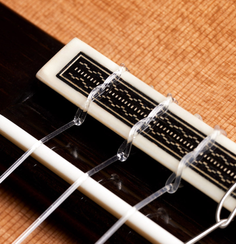 The bridge, tie-block and saddle of a 2024 Jose Vigil classical guitar made of cedar and CSA rosewood.