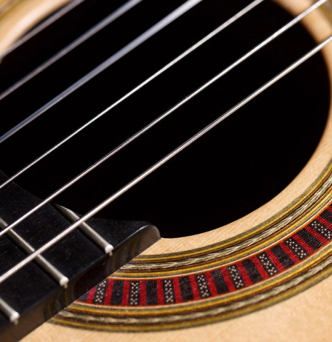 The nylon strings and rosette of a 2015 Otto Vowinkel classical guitar made of spruce and CSA rosewood