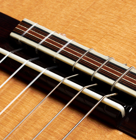 The bridge, tie-block and saddle of a 2024 Otto Vowinkel "2a Double Top" classical guitar made of cedar and Indian rosewood