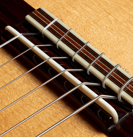 The bridge, tie-block and saddle of an Otto Vowinkel "2a Baritone" classical guitar made with spruce top and Indian rosewood back and sides.