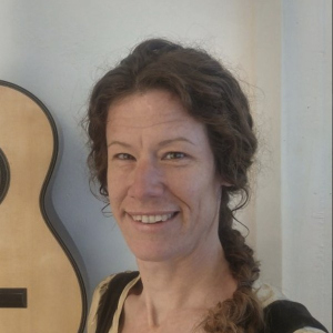 Julia Wenzel smiling beside one of her classical guitars