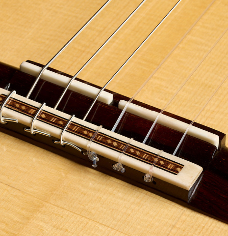 The bridge, tie-block and saddle of a 2026 Fructuoso Zalapa "Romanillos" classical guitar made of spruce and Kingwood