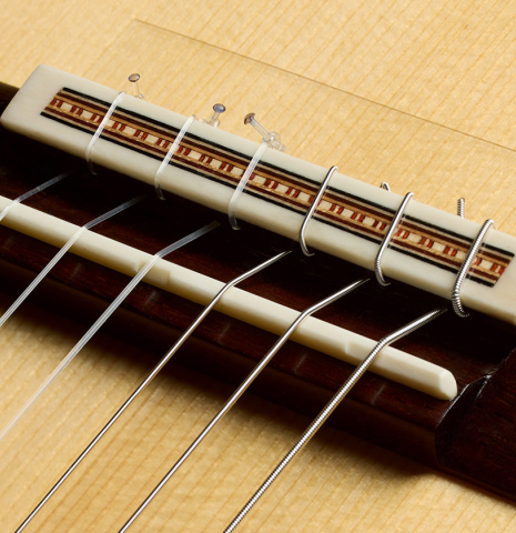 The bridge, tie-block and saddle of a 2025 Fructuoso Zalapa "Romanillos" classical guitar made of spruce and maple