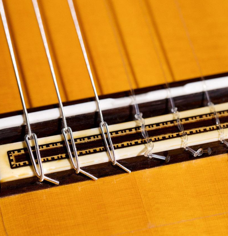 The bridge, tie-block and saddle of a 2016 Francisco Barba CD/MH Flamenco guitar made with cedar top and mahogany back and sides