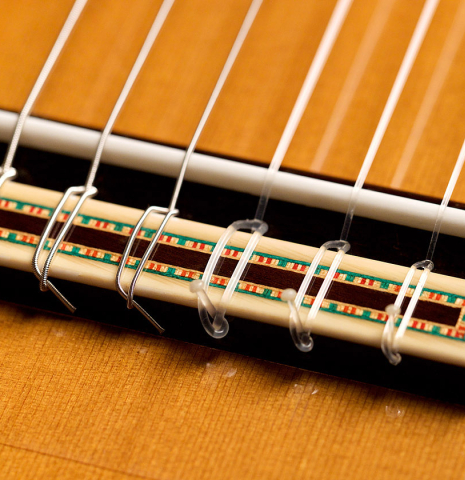 The bridge and saddle of a 2022 Francisco Barba flamenco guitar made of cedar and cypress
