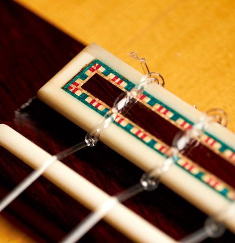 The tie block of a 2015 Francisco Barba flamenco blanca guitar made of spruce and cypress.