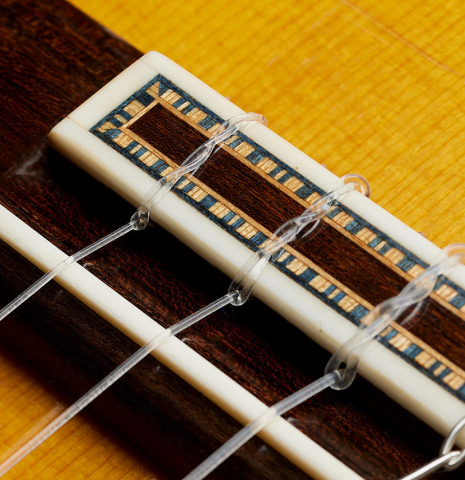 The bridge, tie-block and saddle of a 2003 Francisco Barba flamenco guitar made of spruce and cypress