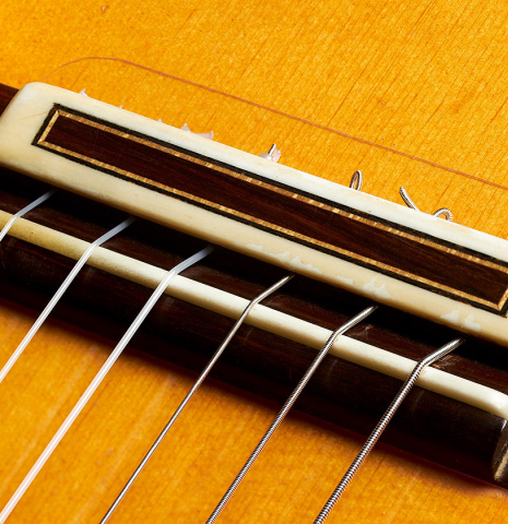 The bridge, tie-block and saddle of a 2002 Jose Lopez Bellido 1aF flamenco guitar made of spruce and cypress