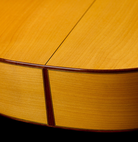 The back and sides at the foot of a 2012 Ron Bushman w/pegs flamenco guitar made of spruce and cypress