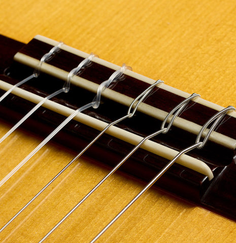 The bridge, tie-block and saddle of a 2012 Ron Bushman w/pegs flamenco guitar made of spruce and cypress
