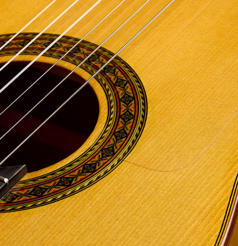 The soundboard and rosette of a 2012 Ron Bushman w/pegs flamenco guitar made of spruce and cypress