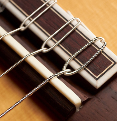 The bridge, tie-block and saddle of a 2015 Hermanos Camps "Primera Negra" flamenco guitar made of spruce and Indian rosewood
